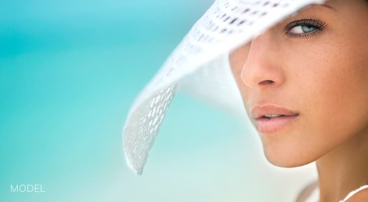 Woman on beach wearing a white sun hat