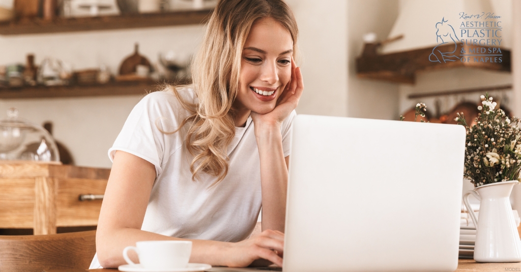 A woman smiles while working on a laptop (MODEL) Kent V. Hasen, MD Logo