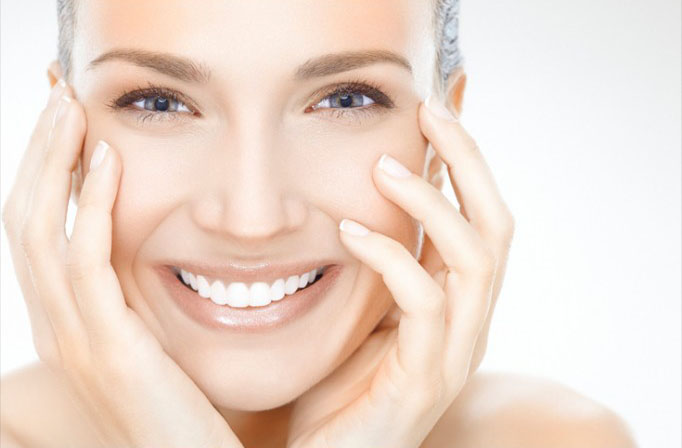 Smiling woman with clear skin with hands on her face