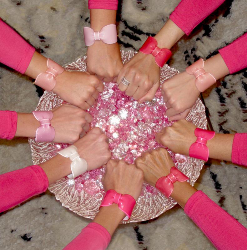 Hands stretching from arms in pink sleeves reaching into bowl with pink baubles