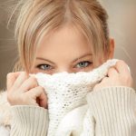 blonde woman hiding behind her sweater