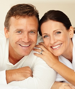 Older model couple with females hand on males shoulder smiling