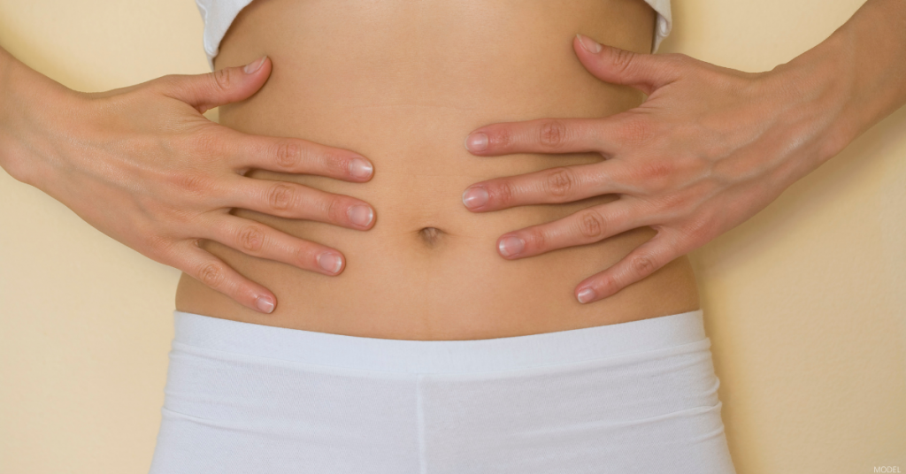 A woman touches her stomach.