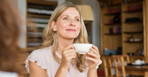 A woman enjoys a cup of coffee with her friend.