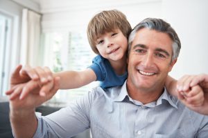 dad carrying young son on his shoulders