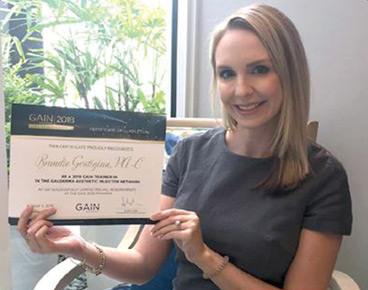 Brandie smiling and holding her GAIN Galderma's certificate.