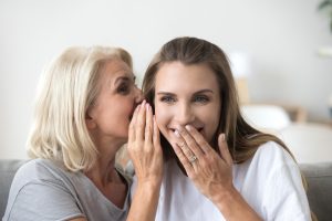Older woman whispering into younger woman\'s ear