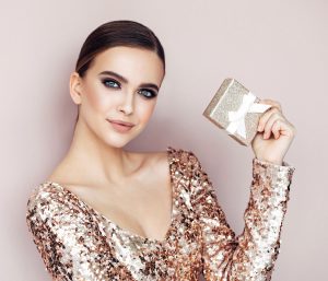 Glamorous model in shimmery dress holding gift box