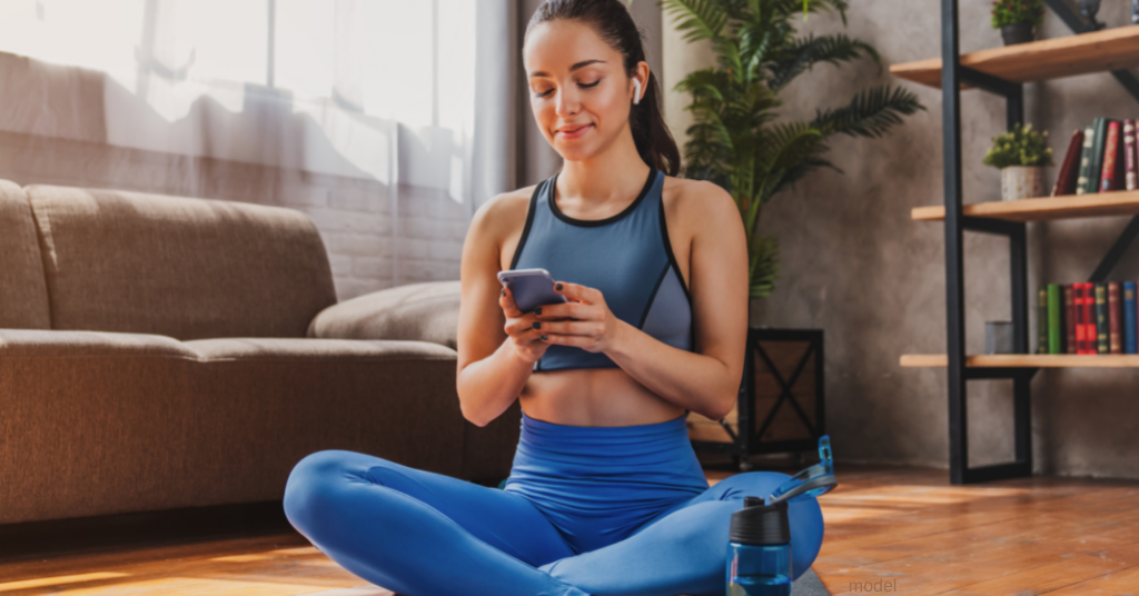 Woman sitting on yoga mat reading about CoolSculpting