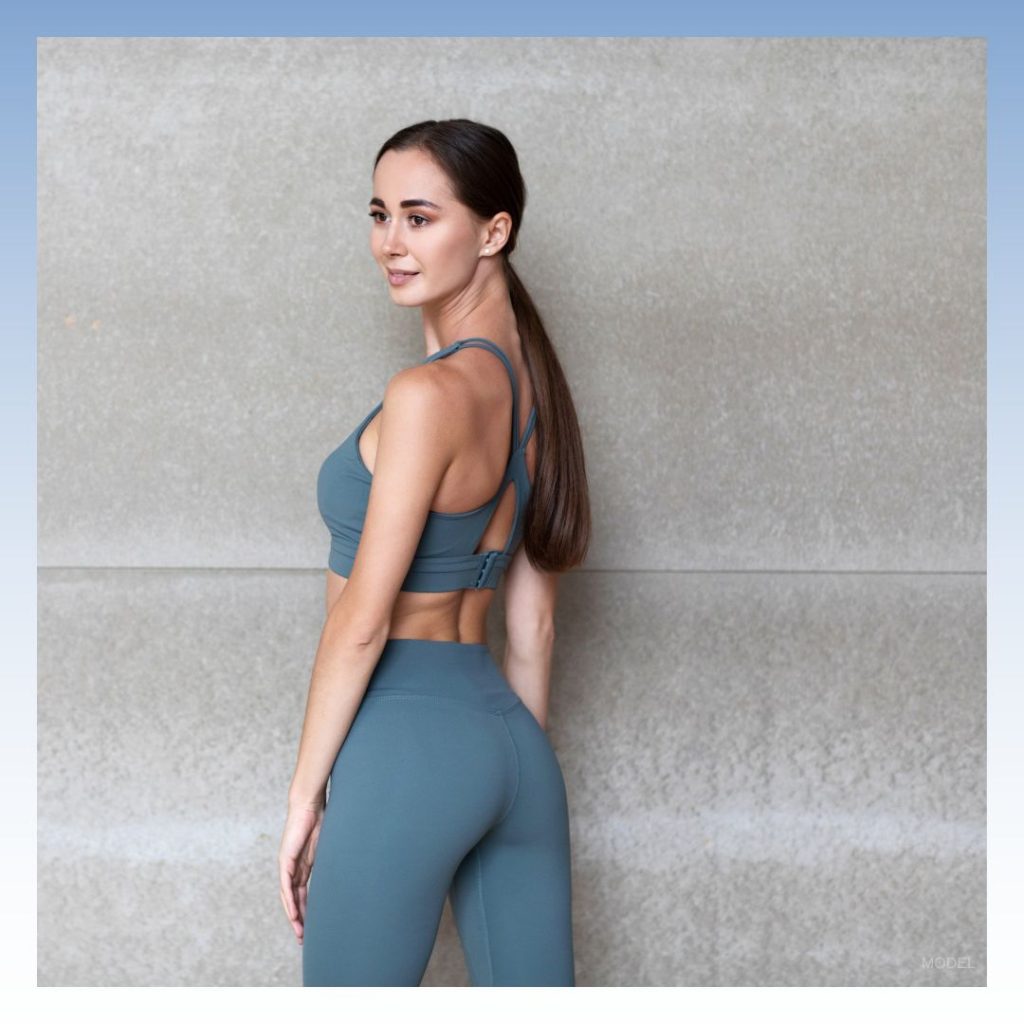 Woman in sports bra and leggings looking over her shoulder (model)