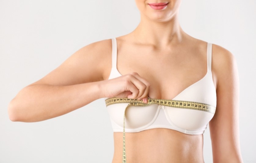 a person measuring their bra size with a tape measure (MODEL)