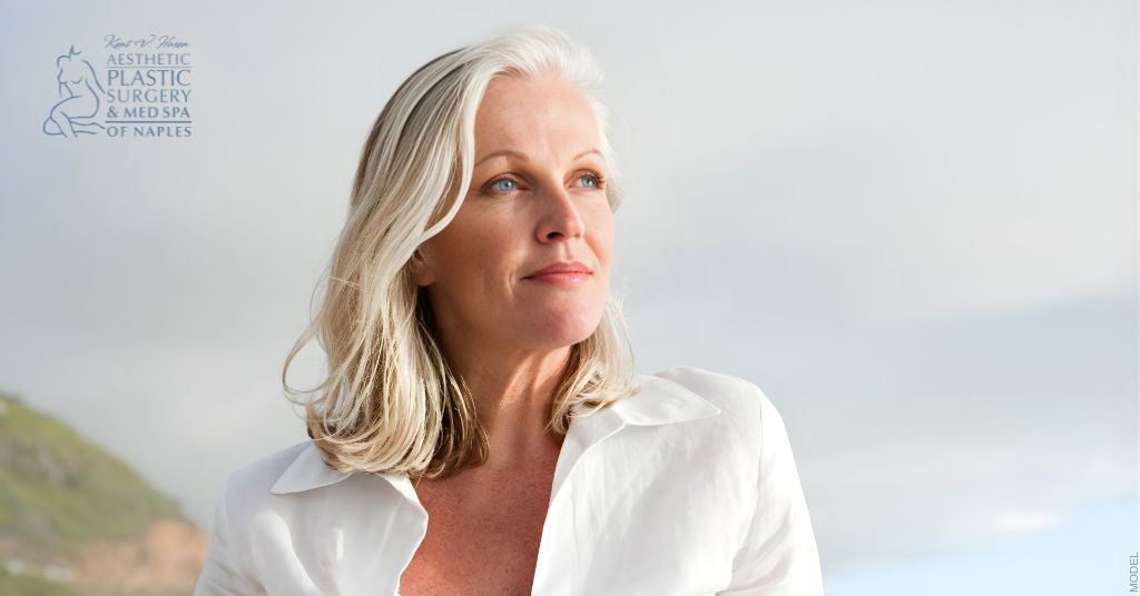 Mature woman at the beach looking at the sky. (Model)